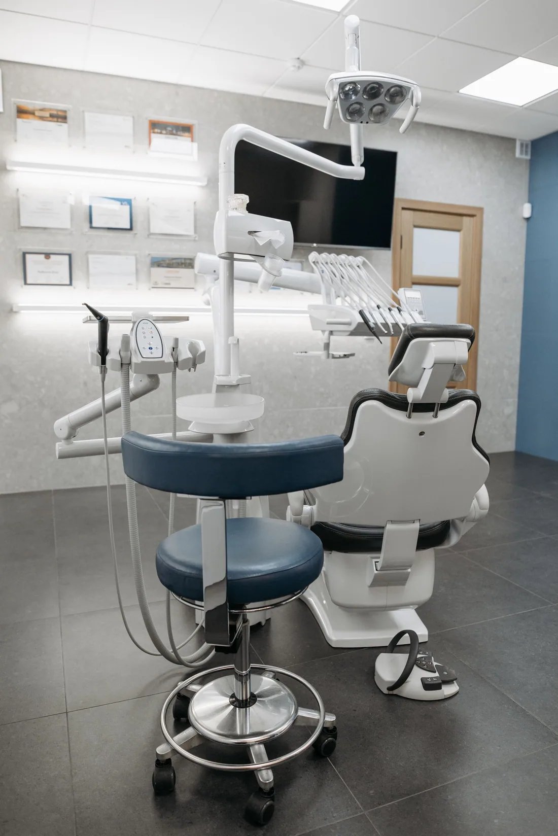 A modern dental treatment room with a patient chair and clinical equipment