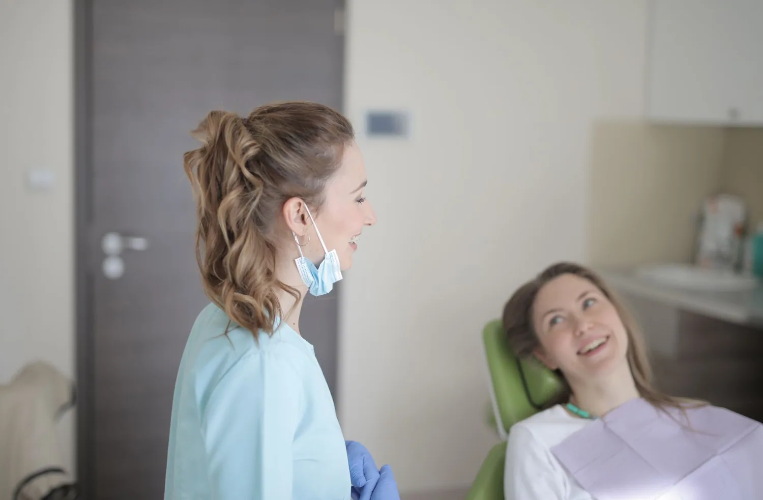 A dental professional talks with a patient seated in a treatment room