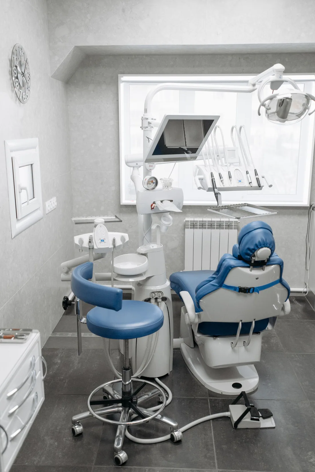 A bright dental treatment room with a blue chair and clinical equipment